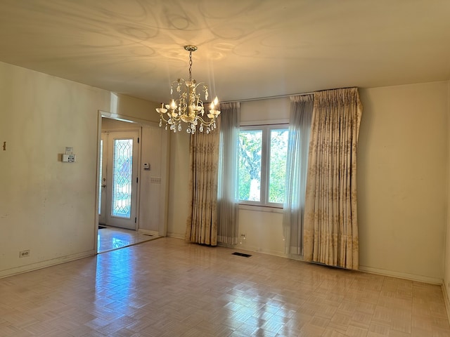 spare room featuring light parquet flooring and a chandelier