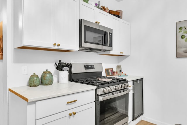 kitchen featuring appliances with stainless steel finishes, white cabinetry, and light stone counters