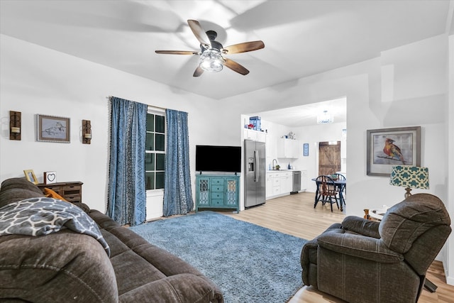 living room with ceiling fan, light hardwood / wood-style flooring, and sink