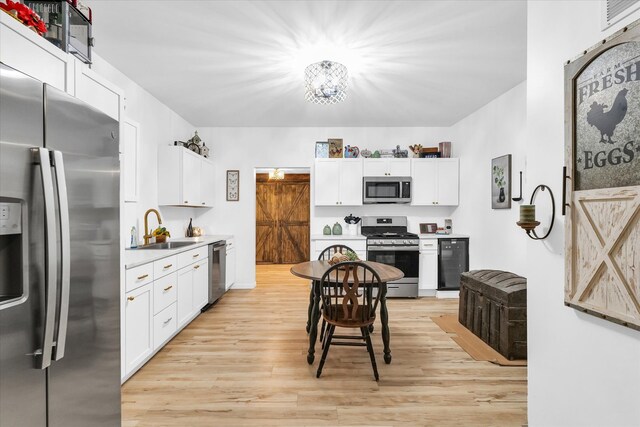 kitchen featuring white cabinets, light wood-type flooring, sink, and appliances with stainless steel finishes