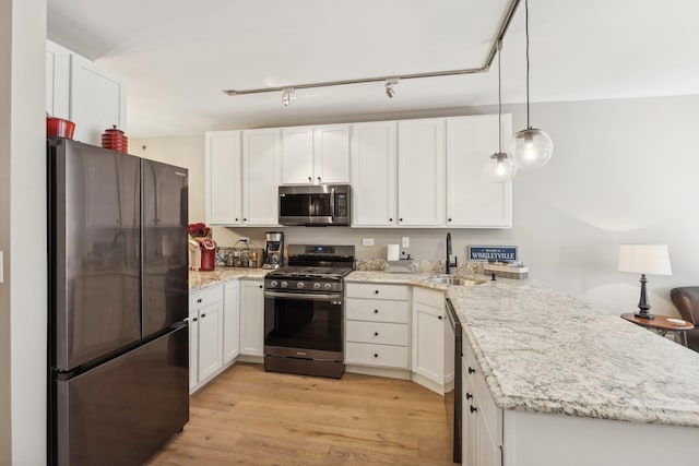 kitchen featuring kitchen peninsula, appliances with stainless steel finishes, sink, pendant lighting, and white cabinetry