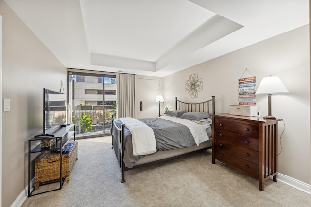 bedroom featuring access to exterior, a tray ceiling, and light colored carpet