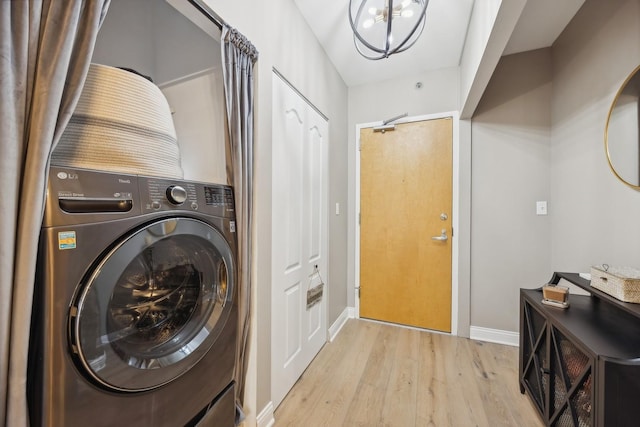 clothes washing area featuring an inviting chandelier, light hardwood / wood-style floors, and washer / dryer