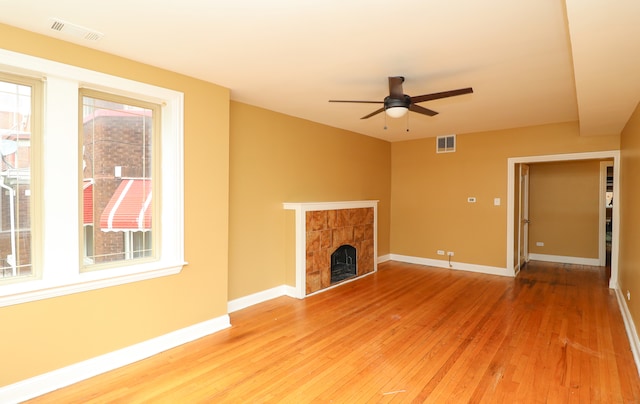 unfurnished living room with ceiling fan, hardwood / wood-style flooring, and a tile fireplace