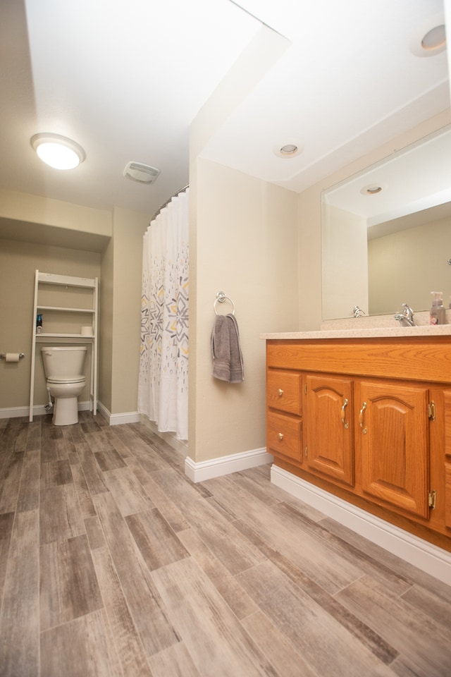 bathroom featuring vanity, toilet, curtained shower, and hardwood / wood-style floors