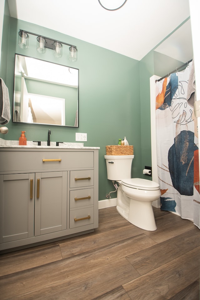 bathroom featuring vanity, toilet, hardwood / wood-style flooring, and curtained shower