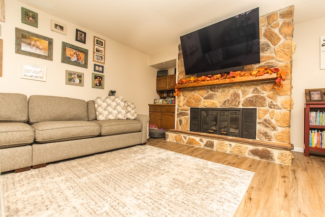 living room with a stone fireplace and hardwood / wood-style flooring