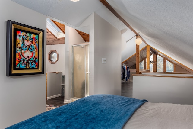 bedroom with dark wood-type flooring, vaulted ceiling with skylight, and a textured ceiling