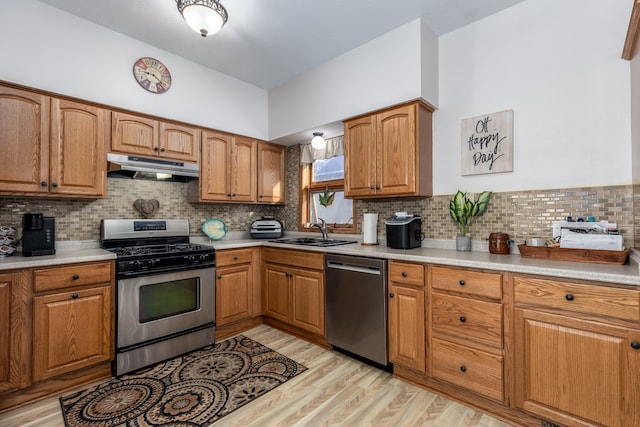 kitchen featuring appliances with stainless steel finishes, decorative backsplash, sink, and light wood-type flooring