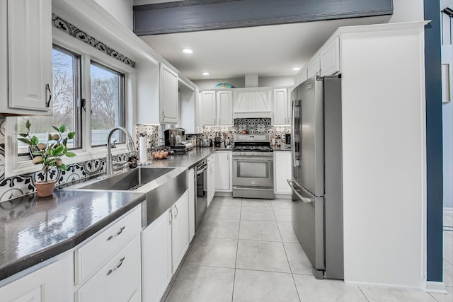 kitchen with tasteful backsplash, stainless steel appliances, sink, light tile patterned floors, and white cabinetry