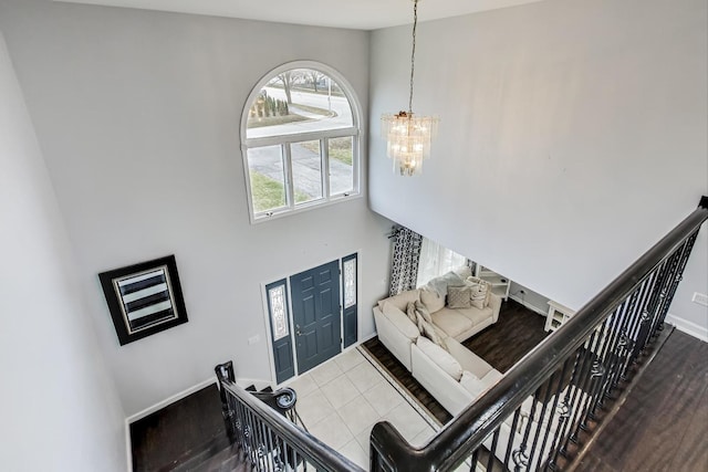 staircase with tile patterned flooring, a high ceiling, and a notable chandelier