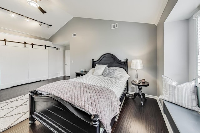 bedroom with a barn door, dark wood-type flooring, ceiling fan, and lofted ceiling