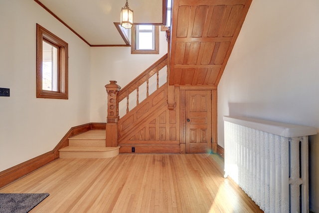 stairway featuring wooden ceiling, hardwood / wood-style flooring, plenty of natural light, and radiator heating unit