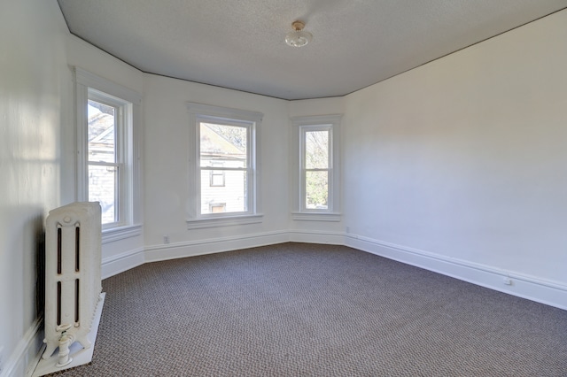 unfurnished room featuring carpet, radiator heating unit, and a textured ceiling