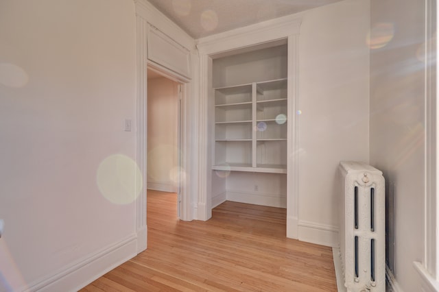 hallway featuring radiator, a textured ceiling, and light hardwood / wood-style flooring