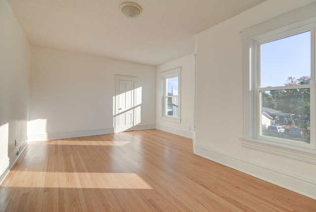 spare room featuring light hardwood / wood-style floors and a textured ceiling