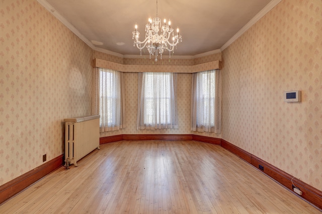 spare room featuring hardwood / wood-style floors, radiator, a notable chandelier, and ornamental molding