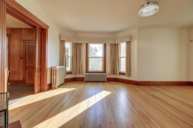 spare room with ornamental molding, light wood-type flooring, radiator heating unit, and a notable chandelier