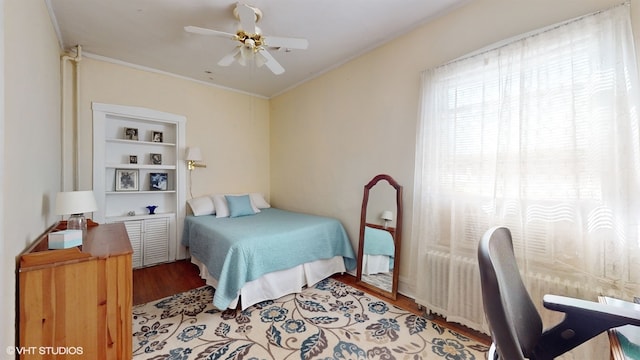 bedroom featuring hardwood / wood-style floors, radiator, ceiling fan, and crown molding