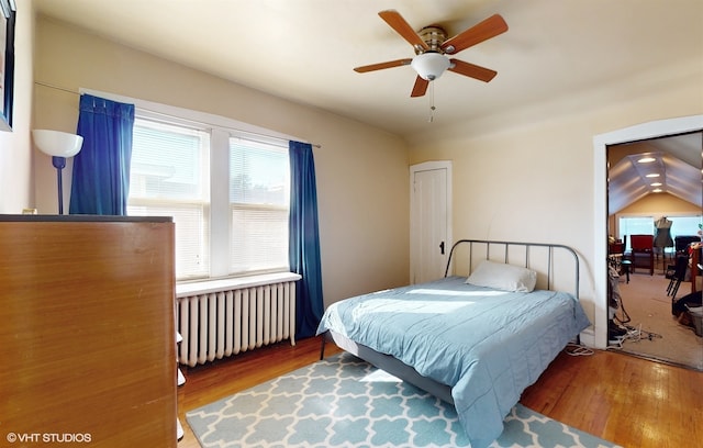 bedroom with hardwood / wood-style flooring, ceiling fan, radiator heating unit, and lofted ceiling