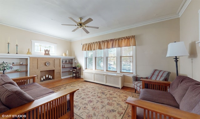 living room featuring a brick fireplace, light hardwood / wood-style floors, ceiling fan, and ornamental molding