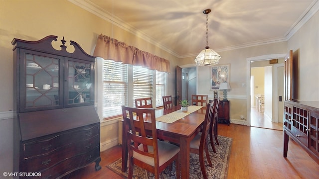 dining space featuring hardwood / wood-style flooring, an inviting chandelier, and ornamental molding