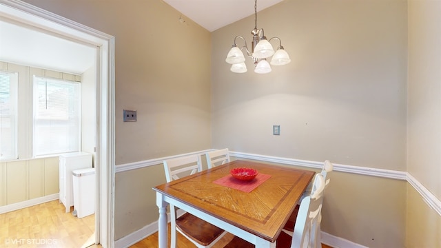 dining space with light wood-type flooring and a notable chandelier