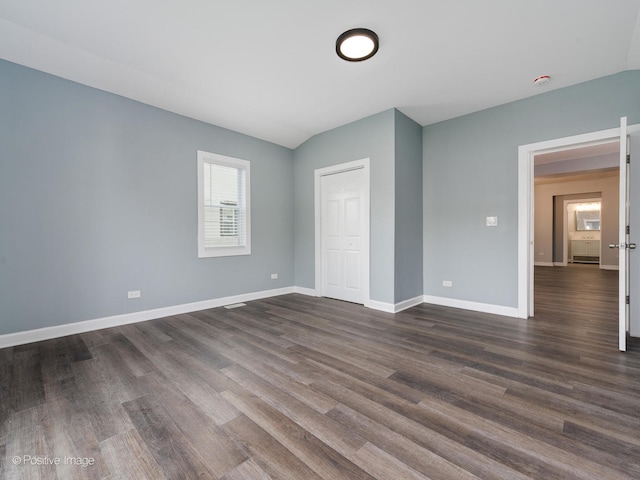 unfurnished bedroom with a closet, vaulted ceiling, and dark hardwood / wood-style flooring