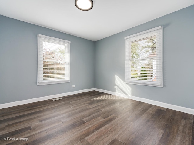 empty room with dark wood-type flooring and a wealth of natural light