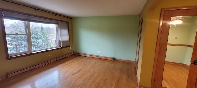 unfurnished room with light wood-type flooring and a baseboard heating unit