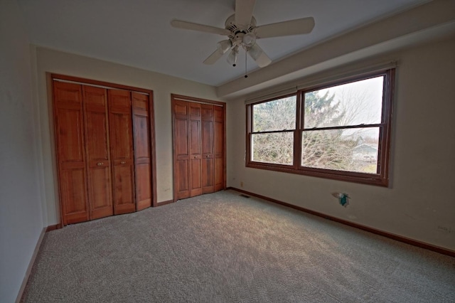 unfurnished bedroom with carpet flooring, multiple closets, and ceiling fan