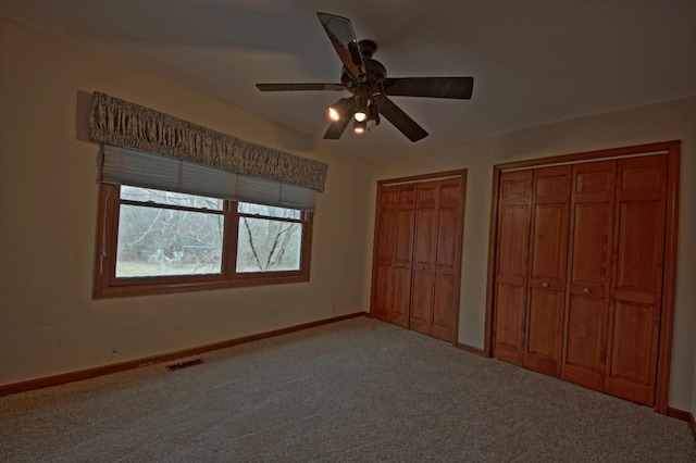 unfurnished bedroom with ceiling fan, carpet floors, and two closets