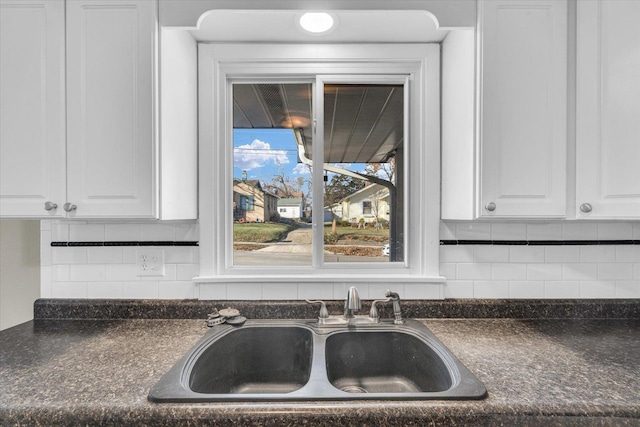 kitchen featuring white cabinets, backsplash, and sink