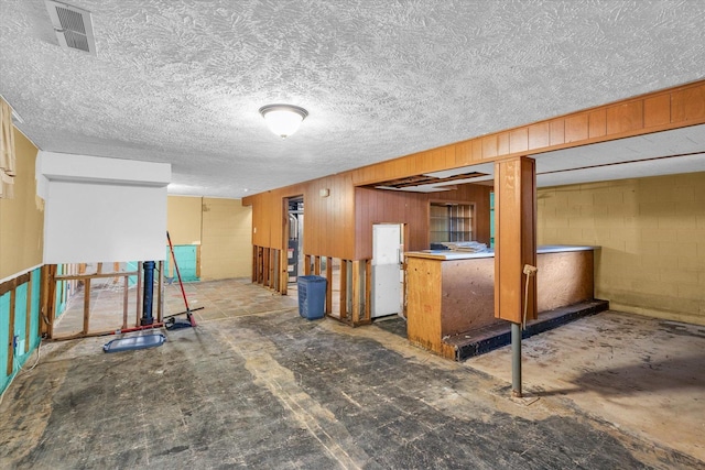 basement featuring wooden walls and a textured ceiling