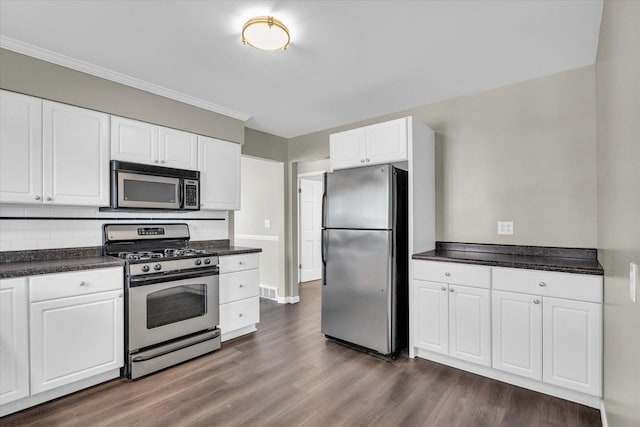 kitchen with dark hardwood / wood-style flooring, backsplash, stainless steel appliances, crown molding, and white cabinets