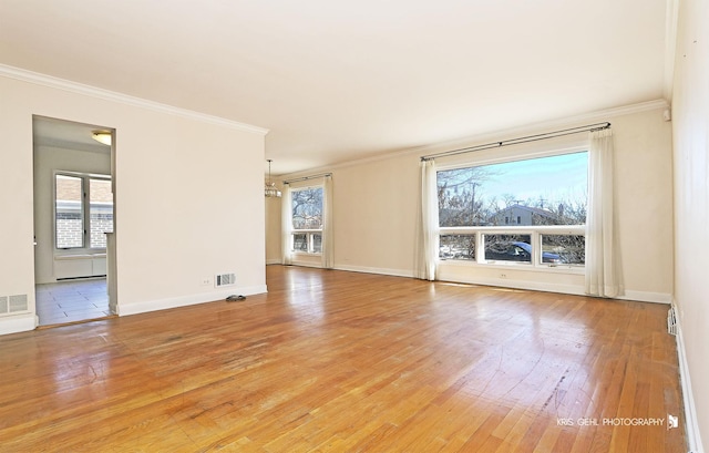 empty room with visible vents, ornamental molding, light wood-style flooring, and baseboards