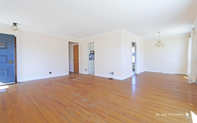 unfurnished living room featuring ornamental molding, a chandelier, light wood-style flooring, and baseboards