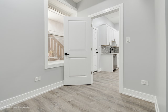 corridor with light hardwood / wood-style flooring and sink