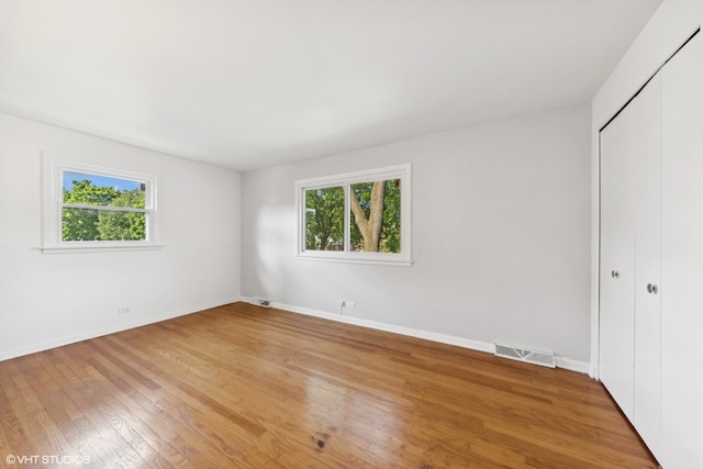 unfurnished bedroom featuring a closet, wood-type flooring, and multiple windows