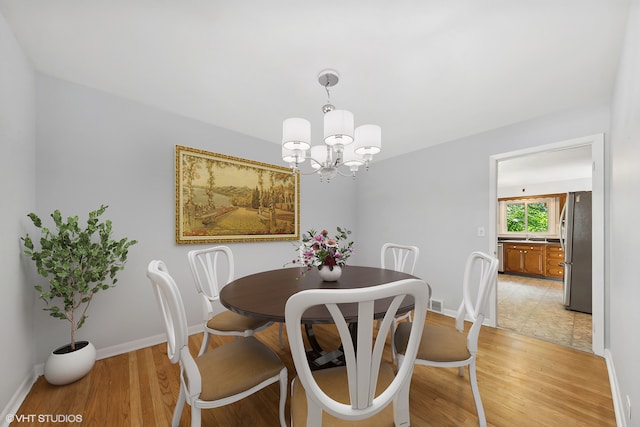 dining area featuring light hardwood / wood-style flooring and an inviting chandelier