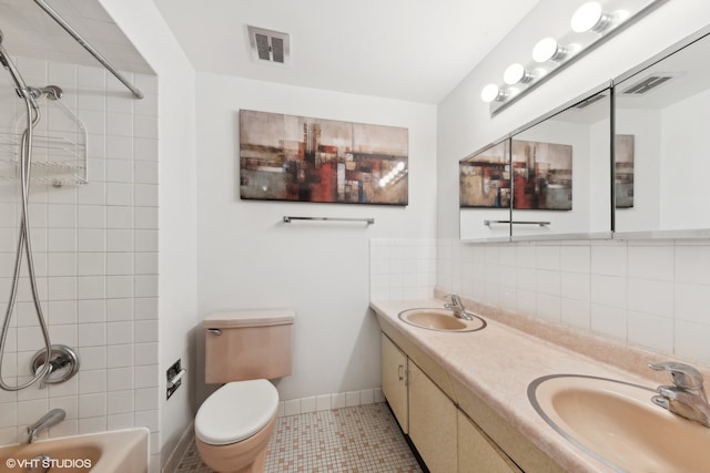 full bathroom featuring toilet, tile patterned flooring, backsplash, tiled shower / bath combo, and vanity