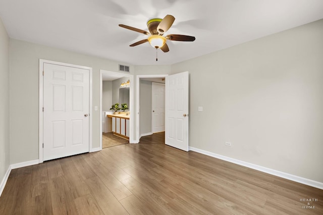 unfurnished bedroom featuring wood-type flooring, ensuite bathroom, and ceiling fan