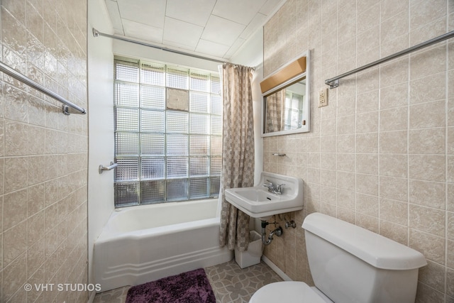 bathroom with toilet, tile walls, and shower / bath combo with shower curtain