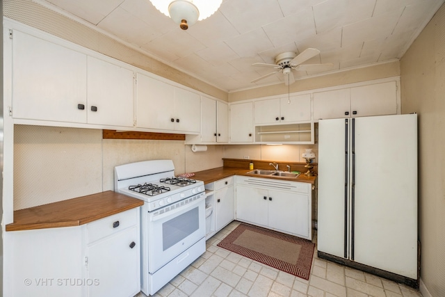 kitchen with white appliances, ceiling fan, white cabinetry, and sink