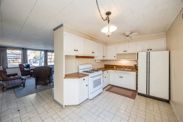 kitchen with sink, ceiling fan, white appliances, white cabinets, and pendant lighting