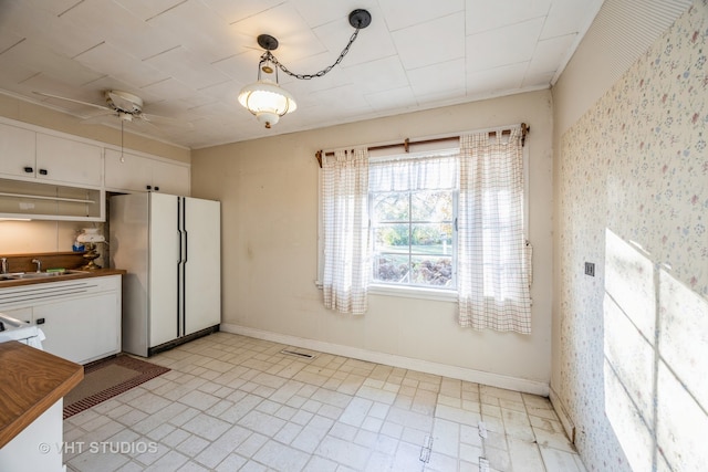 kitchen with white refrigerator, sink, butcher block countertops, ceiling fan, and pendant lighting