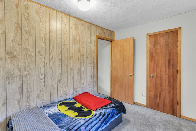 carpeted bedroom with a textured ceiling and wood walls