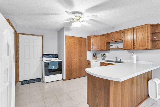 kitchen with white appliances, sink, light tile patterned floors, a textured ceiling, and kitchen peninsula