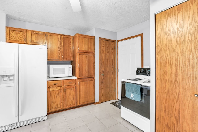 kitchen with a textured ceiling, white appliances, and light tile patterned flooring