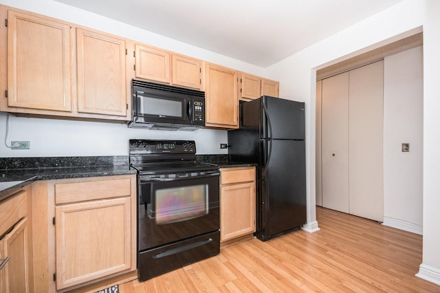 kitchen featuring dark stone countertops, light brown cabinets, and black appliances